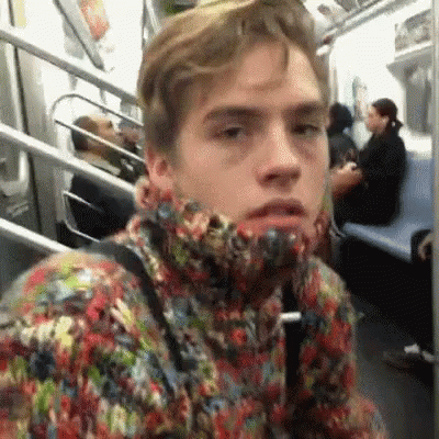 A Man In A Colorful Sweater Is Sitting On A Subway Train . GIF