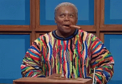 a man in a colorful sweater is standing at a podium and pointing at something .