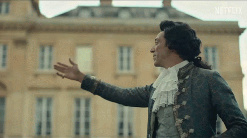 A Man In A Costume Is Standing In Front Of A Building With Netflix Written On The Bottom Of The Screen GIF