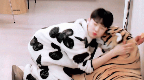 A Man In A Cow Print Pajama Is Petting A Stuffed Animal Tiger GIF