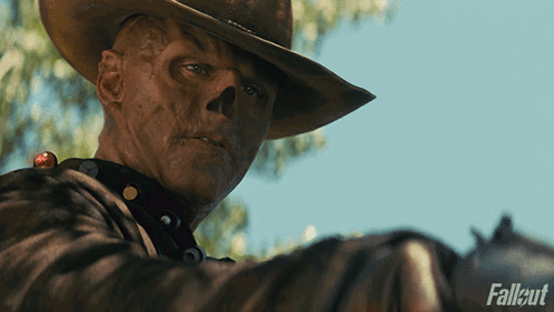 A Man In A Cowboy Hat Is Holding A Gun With Fallout Written On The Bottom Right GIF