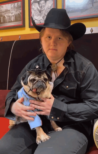 A Man In A Cowboy Hat Is Holding A Pug GIF