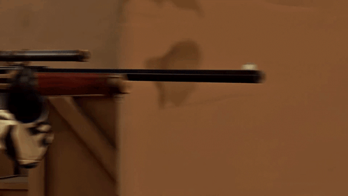 A Man In A Cowboy Hat Is Holding A Rifle In His Right Hand GIF