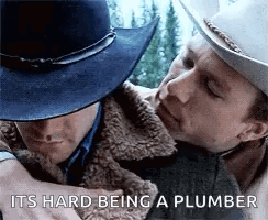 A Man In A Cowboy Hat Is Hugging Another Man . GIF