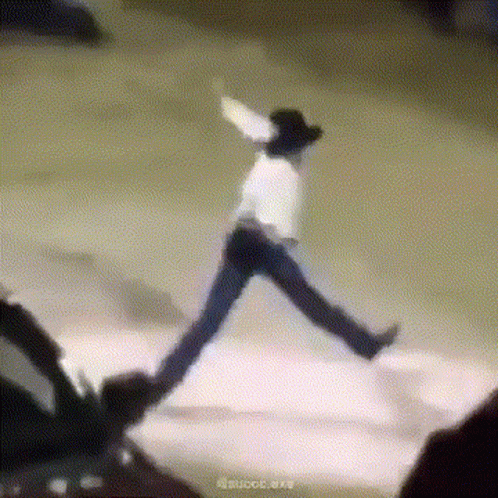 A Man In A Cowboy Hat Is Jumping In The Air While Wearing Jeans And A White Shirt . GIF