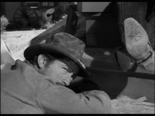 A Man In A Cowboy Hat Is Laying On The Ground . GIF
