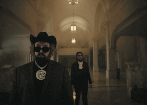 A Man In A Cowboy Hat Is Smoking A Cigarette GIF