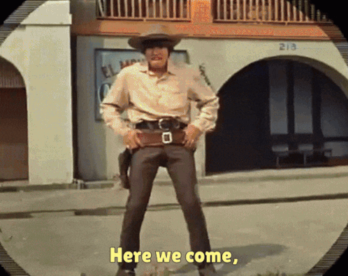 A Man In A Cowboy Hat Is Standing In Front Of A Building That Says 213 On It GIF