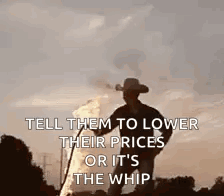 A Man In A Cowboy Hat Is Standing In Front Of A Fire Holding A Whip . GIF