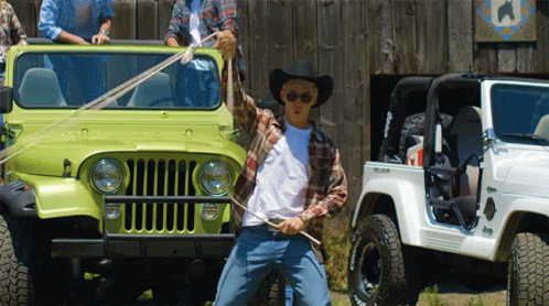A Man In A Cowboy Hat Is Standing In Front Of A Jeep GIF