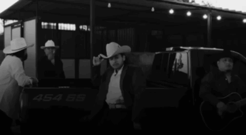 A Man In A Cowboy Hat Is Standing In The Back Of A Truck With The Number 454 On It GIF