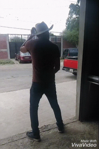 A Man In A Cowboy Hat Is Standing Next To A Red Truck GIF