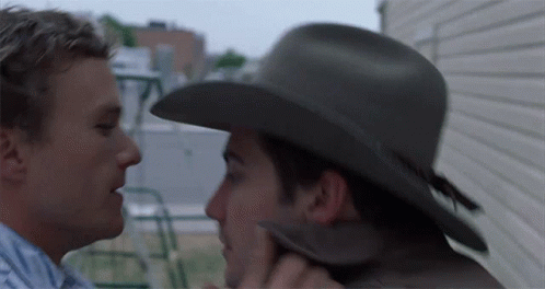 A Man In A Cowboy Hat Kisses Another Man GIF