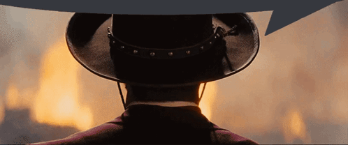 a man in a cowboy hat stands in front of a large fire