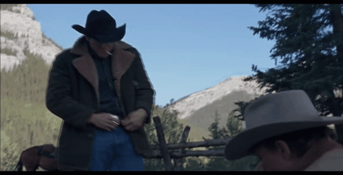 A Man In A Cowboy Hat Stands Next To Another Man GIF