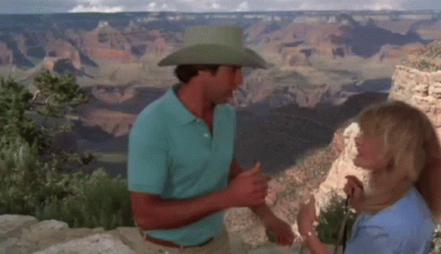 A Man In A Cowboy Hat Talks To A Woman GIF