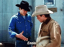A Man In A Cowboy Hat Talks To Another Man In A Blue Shirt Who Says Ennis GIF