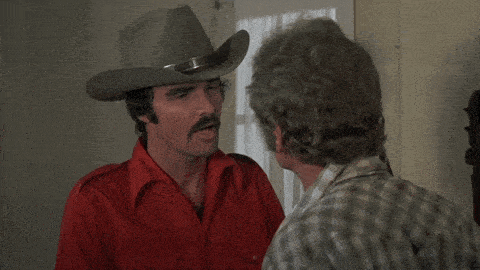 A Man In A Cowboy Hat Talks To Another Man With The Words " For The Good Old American " Above Him GIF