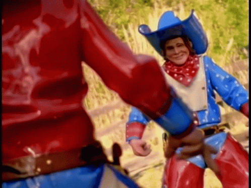 A Man In A Cowboy Outfit Is Holding A Gun GIF