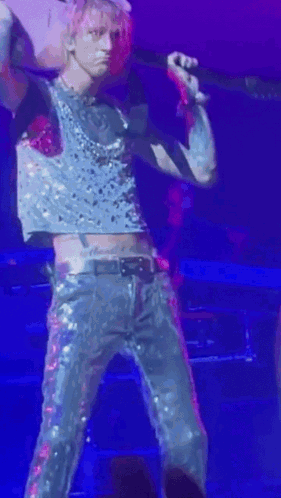 A Man In A Crop Top Is Holding A Guitar And Singing Into A Microphone . GIF