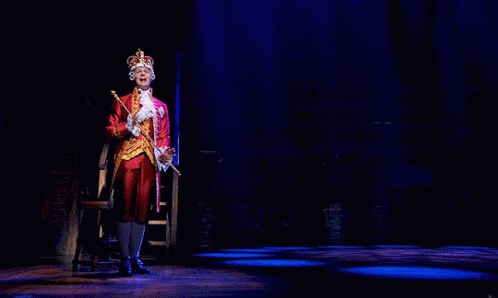 A Man In A Crown Is Holding A Cane GIF