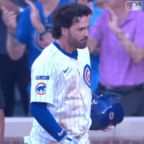 A Man In A Cubs Uniform Is Standing In Front Of A Crowd Applauding GIF