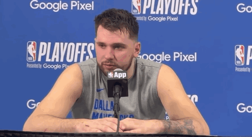 A Man In A Dallas Shirt Is Talking Into A Microphone In Front Of A Google Pixel Sign GIF