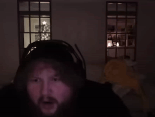 A Man In A Dark Room With A Christmas Tree In The Background Says Genius GIF