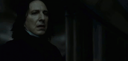 A Man In A Dark Room With A Glowing Light Behind Him GIF