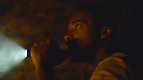 A Man In A Dark Room With A Green Light Shining On Him GIF