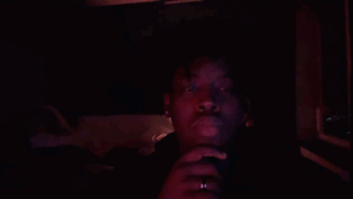 A Man In A Dark Room With A Red Light Shining On His Face GIF