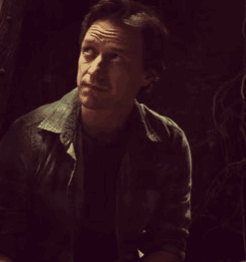 A Man In A Dark Room With His Eyes Closed And A Serious Look On His Face GIF