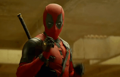 A Man In A Deadpool Costume Is Holding A Sword And Giving The Peace Sign GIF
