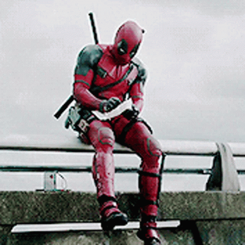 A Man In A Deadpool Costume Is Sitting On A Ledge . GIF