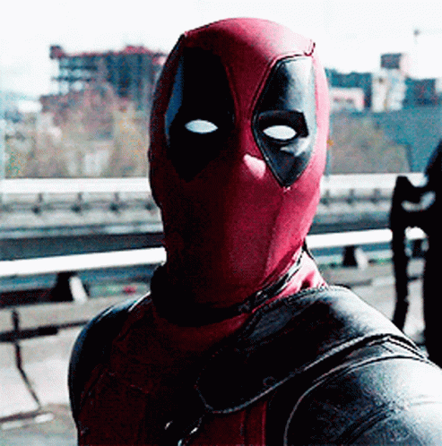 A Man In A Deadpool Costume Is Standing In Front Of A Bridge GIF