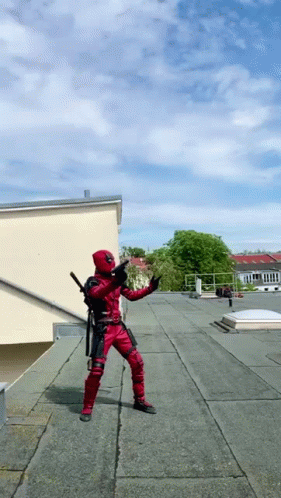 A Man In A Deadpool Costume Is Standing On A Rooftop GIF