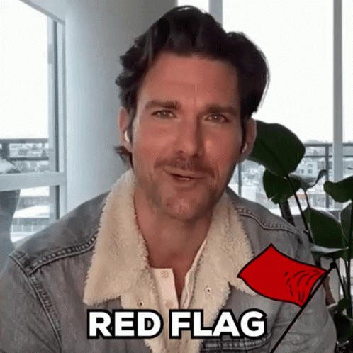 a man in a denim jacket is holding a red flag with the word red flag written on it