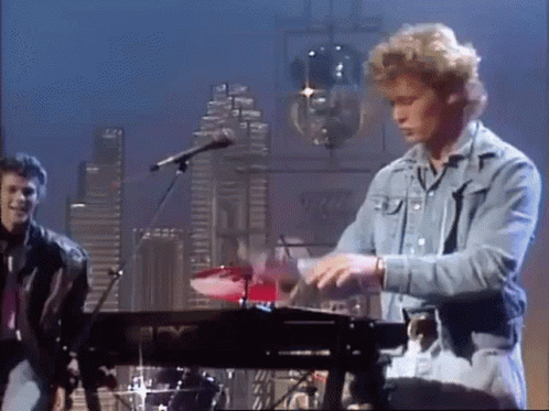 A Man In A Denim Jacket Is Playing A Keyboard GIF