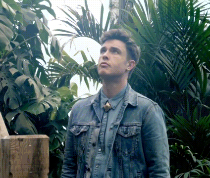 A Man In A Denim Jacket Is Standing In A Jungle GIF