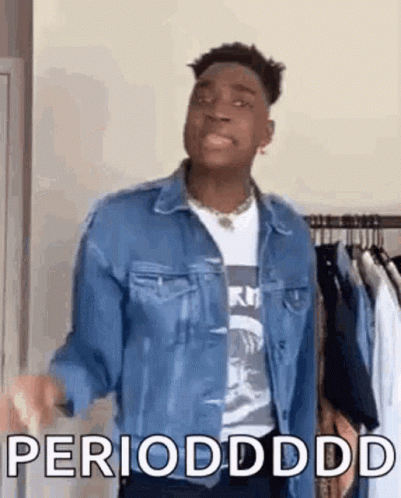 A Man In A Denim Jacket Is Standing In Front Of A Clothes Rack And Says Periodddd . GIF