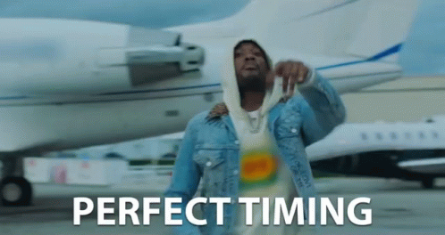 a man in a denim jacket is standing in front of an airplane with the words perfect timing written on the bottom