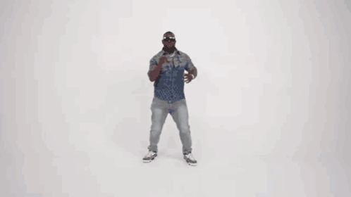 A Man In A Denim Shirt And Jeans Is Dancing In Front Of A White Background . GIF