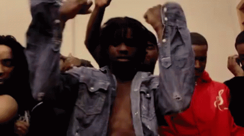 A Man In A Denim Shirt Is Dancing With His Arms In The Air . GIF