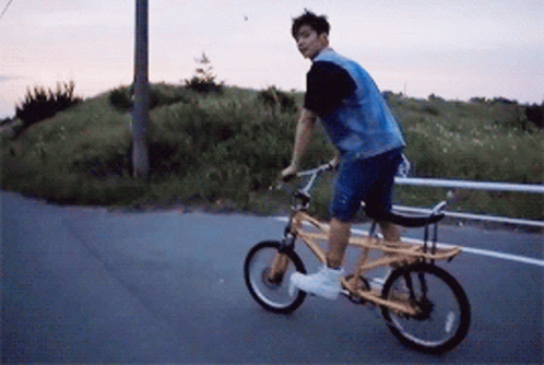 A Man In A Denim Vest Is Riding A Yellow Bike GIF