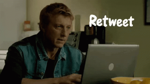 A Man In A Denim Vest Is Using A Laptop With The Word Retweet Above Him GIF