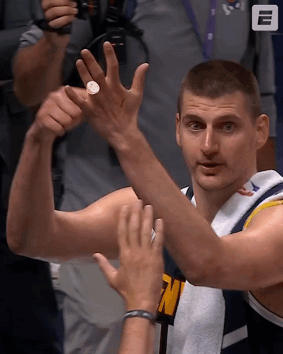 A Man In A Denver Jersey Holds Up A Coin GIF