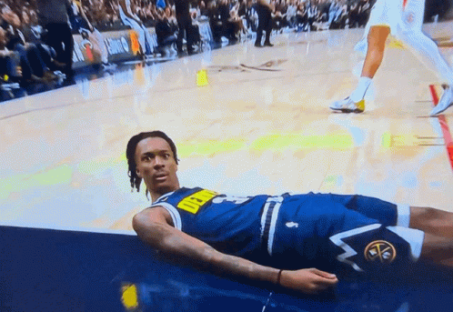a man in a denver nuggets uniform lays on the floor