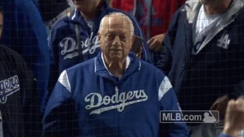 A Man In A Dodgers Jacket Stands In The Crowd GIF