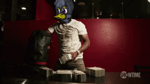 A Man In A Duck Mask Stands In Front Of Stacks Of Money With Showtime Written On The Bottom GIF