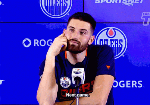 A Man In A Edmonton Oilers T-Shirt Talks Into A Microphone GIF